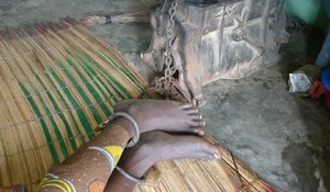 A mentally ill patient shackled to an engine block at the Olaiya Naturalist Hospital in Ibadan, Nigeria. Photo: Rowan Moore Gerety